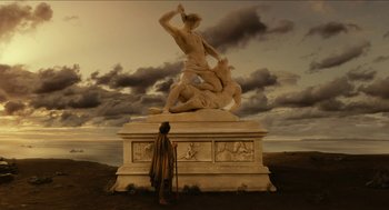 Movie still from “Immortals” (2011), directed by Tarsem Singh – A man standing next to a large statue of a man and a horse; Extreme Wide shot, Low angle