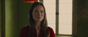 Movie still from “In Time” (2011), directed by Andrew Niccol – A woman in a red shirt standing in front of a window; Close Up shot, Over the shoulder angle