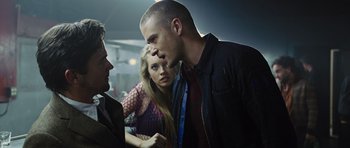 Movie still from “In Time” (2011), directed by Andrew Niccol – Two men and a woman in a dark room; Medium shot, Over the shoulder angle