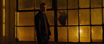 Movie still from “In Time” (2011), directed by Andrew Niccol – A man standing in front of a window at night; Medium shot, Low angle