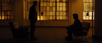 Movie still from “In Time” (2011), directed by Andrew Niccol – Two people standing in front of a window at night; Wide shot, Over the shoulder angle