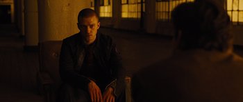 Movie still from “In Time” (2011), directed by Andrew Niccol – A man sitting on the ground in a dark room; Medium shot, Over the shoulder angle