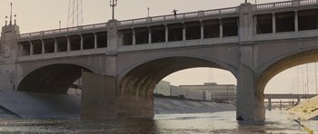 Movie still from “In Time” (2011), directed by Andrew Niccol – A bridge over a body of water near a building; Extreme Wide shot, Over the shoulder angle