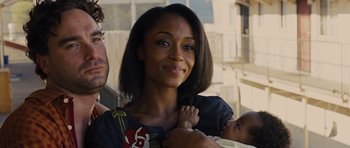 Movie still from “In Time” (2011), directed by Andrew Niccol – A woman holding a baby in her arms and smiling; Close Up shot, Over the shoulder angle