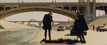 Movie still from “In Time” (2011), directed by Andrew Niccol – A man standing on the side of a road next to a dead body; Wide shot, High angle