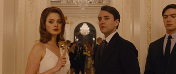 Movie still from “In Time” (2011), directed by Andrew Niccol – A man and a woman standing next to each other holding champagne flutes; Medium shot, Low angle