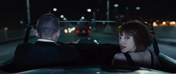 Movie still from “In Time” (2011), directed by Andrew Niccol – A man and a woman sitting in the back of a car; Medium shot, Over the shoulder angle