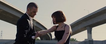 Movie still from “In Time” (2011), directed by Andrew Niccol – A man and a woman holding hands in front of an overpass; Medium shot, Low angle