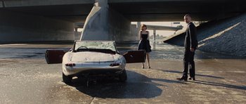 Movie still from “In Time” (2011), directed by Andrew Niccol – A woman standing next to an abandoned car; Wide shot, High angle