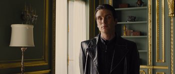 Movie still from “In Time” (2011), directed by Andrew Niccol – A man wearing a leather jacket standing in a room; Medium shot, Low angle