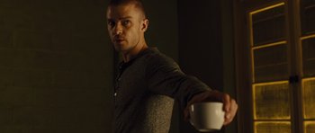 Movie still from “In Time” (2011), directed by Andrew Niccol – A man is holding a coffee cup in his hand; Medium shot, Low angle