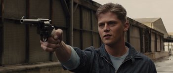 Movie still from “In Time” (2011), directed by Andrew Niccol – A man holding a gun in his hand; Close Up shot, Over the shoulder angle