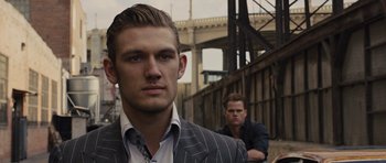 Movie still from “In Time” (2011), directed by Andrew Niccol – A man in a pinstriped suit standing next to another man; Close Up shot, Over the shoulder angle