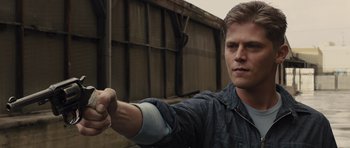 Movie still from “In Time” (2011), directed by Andrew Niccol – A man holding something in his right hand while standing outside; Close Up shot, Over the shoulder angle