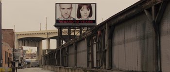 Movie still from “In Time” (2011), directed by Andrew Niccol – A billboard with a man and a woman on top of it; Extreme Wide shot, High angle