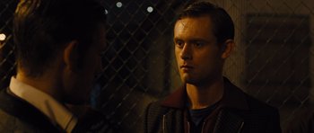 Movie still from “In Time” (2011), directed by Andrew Niccol – A man standing in front of a chain link fence at night; Close Up shot, Over the shoulder angle