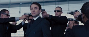 Movie still from “In Time” (2011), directed by Andrew Niccol – A group of men in suits and ties holding guns; Close Up shot, Over the shoulder angle
