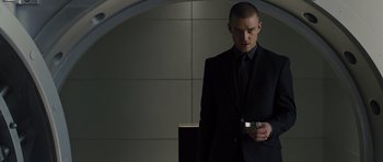 Movie still from “In Time” (2011), directed by Andrew Niccol – A man in a suit and tie holding a cell phone; Medium shot, Low angle