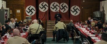 Movie still from “Imperium” (2016), directed by Daniel Ragussis – A group of people sitting in front of a nazi flag; Wide shot, High angle