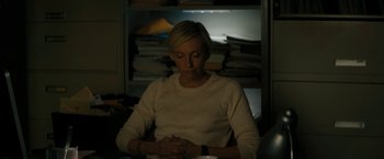 Movie still from “Imperium” (2016), directed by Daniel Ragussis – A woman sitting at a table in a room; Medium shot, High angle