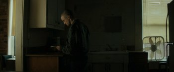 Movie still from “Imperium” (2016), directed by Daniel Ragussis – A man standing in a dark kitchen next to a counter; Medium shot, Low angle