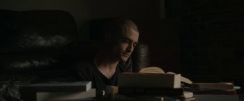 Movie still from “Imperium” (2016), directed by Daniel Ragussis – A man sitting at a table reading a book; Medium shot, High angle