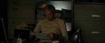 Movie still from “Imperium” (2016), directed by Daniel Ragussis – A woman sitting at a desk looking at papers; Medium shot, High angle
