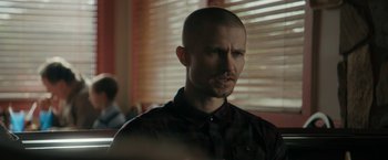 Movie still from “Imperium” (2016), directed by Daniel Ragussis – A man with a shaved head is looking at the camera; Close Up shot, Over the shoulder angle