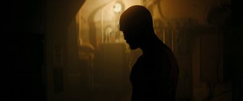 Movie still from “Imperium” (2016), directed by Daniel Ragussis – A man standing in a room with a clock in the background; Medium shot, Low angle