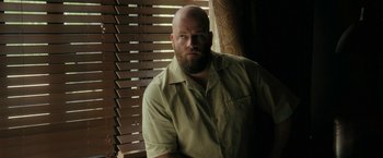 Movie still from “Imperium” (2016), directed by Daniel Ragussis – A man with a beard is standing in front of a window; Medium shot, Low angle