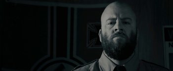Movie still from “Imperium” (2016), directed by Daniel Ragussis – A man with a bald head and a beard; Close Up shot, Low angle