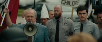 Movie still from “Imperium” (2016), directed by Daniel Ragussis – A man in a suit is holding a megaphone; Medium shot, Over the shoulder angle