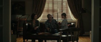 Movie still from “Imperium” (2016), directed by Daniel Ragussis – A man and a woman sitting on a couch with a little girl; Wide shot, Over the shoulder angle