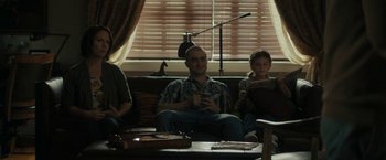 Movie still from “Imperium” (2016), directed by Daniel Ragussis – A man and two women sitting on top of a brown couch; Wide shot, Over the shoulder angle