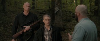 Movie still from “Imperium” (2016), directed by Daniel Ragussis – A man in a plaid shirt is holding a rifle; Medium shot, Over the shoulder angle