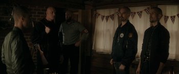 Movie still from “Imperium” (2016), directed by Daniel Ragussis – A group of men standing next to each other in front of a window; Medium shot, Over the shoulder angle