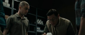 Movie still from “Imperium” (2016), directed by Daniel Ragussis – Two men are looking at something in a jar; Medium shot, Over the shoulder angle