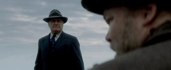 Movie still from “In Dubious Battle” (2016), directed by James Franco – A man in a suit and hat standing next to another man in a hat; Medium shot, Over the shoulder angle