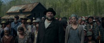 Movie still from “In Dubious Battle” (2016), directed by James Franco – A man and a woman are standing in front of a group of people; Medium shot, Low angle