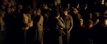 Movie still from “In Dubious Battle” (2016), directed by James Franco – A group of people standing around in a room; Medium shot, Over the shoulder angle