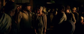 Movie still from “In Dubious Battle” (2016), directed by James Franco – A group of people standing in a dark room; Medium shot, Low angle