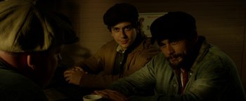 Movie still from “In Dubious Battle” (2016), directed by James Franco – Two young men sitting at a table with a cup of coffee; Medium shot, Low angle