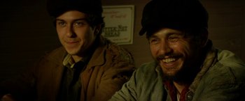 Movie still from “In Dubious Battle” (2016), directed by James Franco – Two men smiling for the camera while wearing hats; Close Up shot, Low angle
