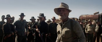 Movie still from “In Dubious Battle” (2016), directed by James Franco – A group of men standing next to each other holding guns; Medium shot, Over the shoulder angle