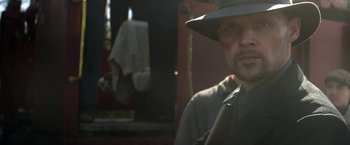 Movie still from “In Dubious Battle” (2016), directed by James Franco – A man with a hat and a gun in his hands; Close Up shot, Over the shoulder angle