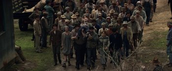 Movie still from “In Dubious Battle” (2016), directed by James Franco – A group of people walking down a dirt road; Wide shot, High angle