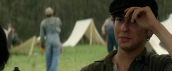 Movie still from “In Dubious Battle” (2016), directed by James Franco – A man in a hat is standing in a field; Close Up shot, Over the shoulder angle