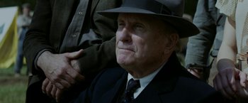 Movie still from “In Dubious Battle” (2016), directed by James Franco – An older man wearing a suit and a hat; Close Up shot, Over the shoulder angle