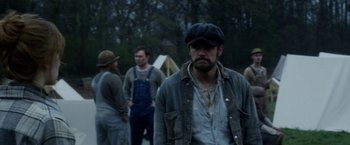 Movie still from “In Dubious Battle” (2016), directed by James Franco – A group of people standing around a forest; Medium shot, Over the shoulder angle