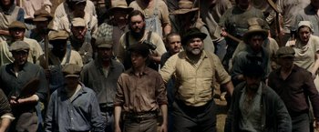 Movie still from “In Dubious Battle” (2016), directed by James Franco – A group of men standing next to each other in a field; Medium shot, High angle